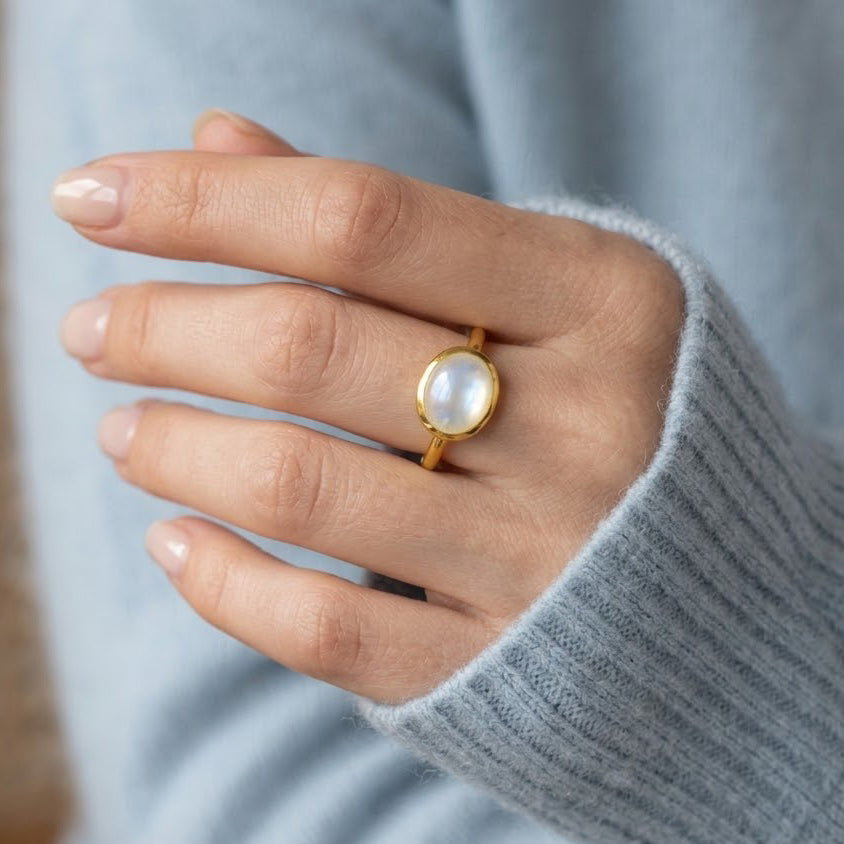 Mother of pearl oval gemstone ring worn on hand with a cozy sweater, shown as a minimalist everyday gold ring.