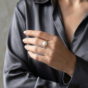 Oval mother of pearl ring worn on hand with a dark blouse, styled as an elegant gemstone ring for everyday wear.