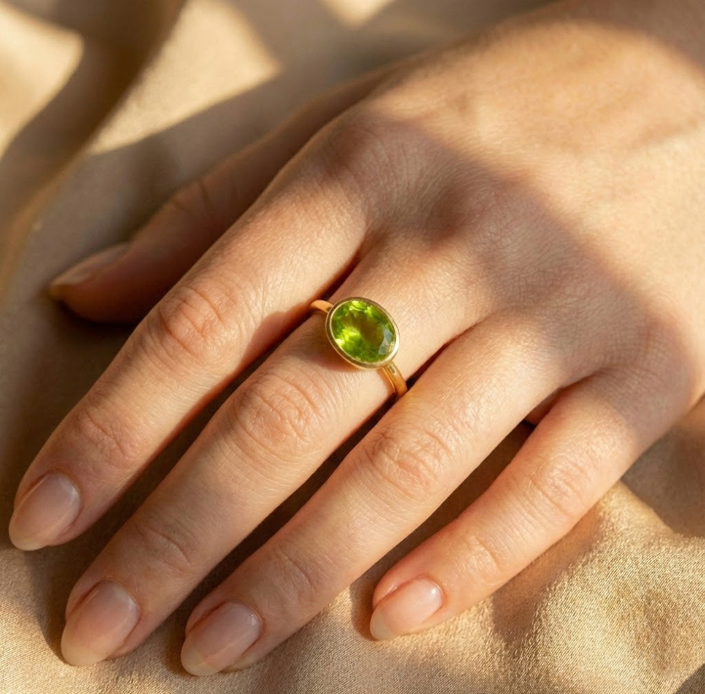 Minimalist oval peridot ring worn on hand, green gemstone August birthstone jewelry for everyday wear