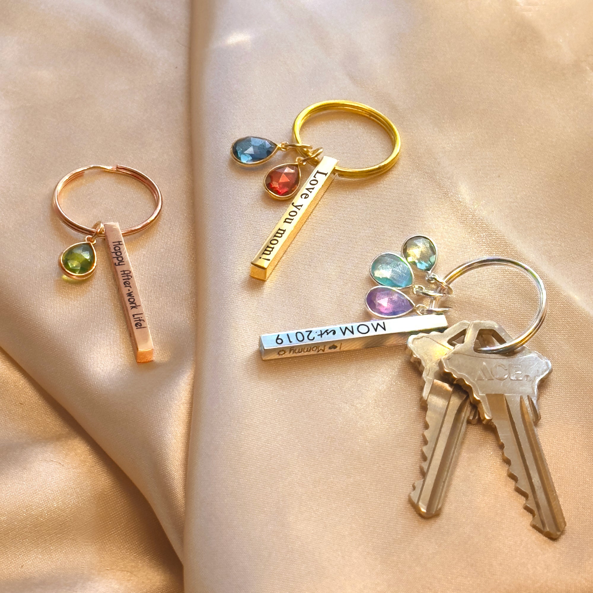 Silver and gold personalized mom keychains styled alongside keys to show scale and shine. Each dainty 3D bar (40×4 mm) is engraved with names and paired with one or more bezel-set birthstones for children or grandchildren. Minimalist and durable, this custom bar keychain with birthstones is perfect for new moms, mother-in-law gifts, and proud grandmas who want a meaningful accessory they carry every day.