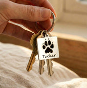 Personalized pet paw print keychain shown attached to a set of house keys, featuring a custom engraved dog paw print and pet name on a square stainless steel charm. This custom pet memorial keychain is handcrafted as a meaningful keepsake for dog and cat owners, pet parents, and animal lovers. Ideal as a sympathy gift, pet loss remembrance, or everyday personalized pet accessory, designed to keep a beloved pet close at all times.