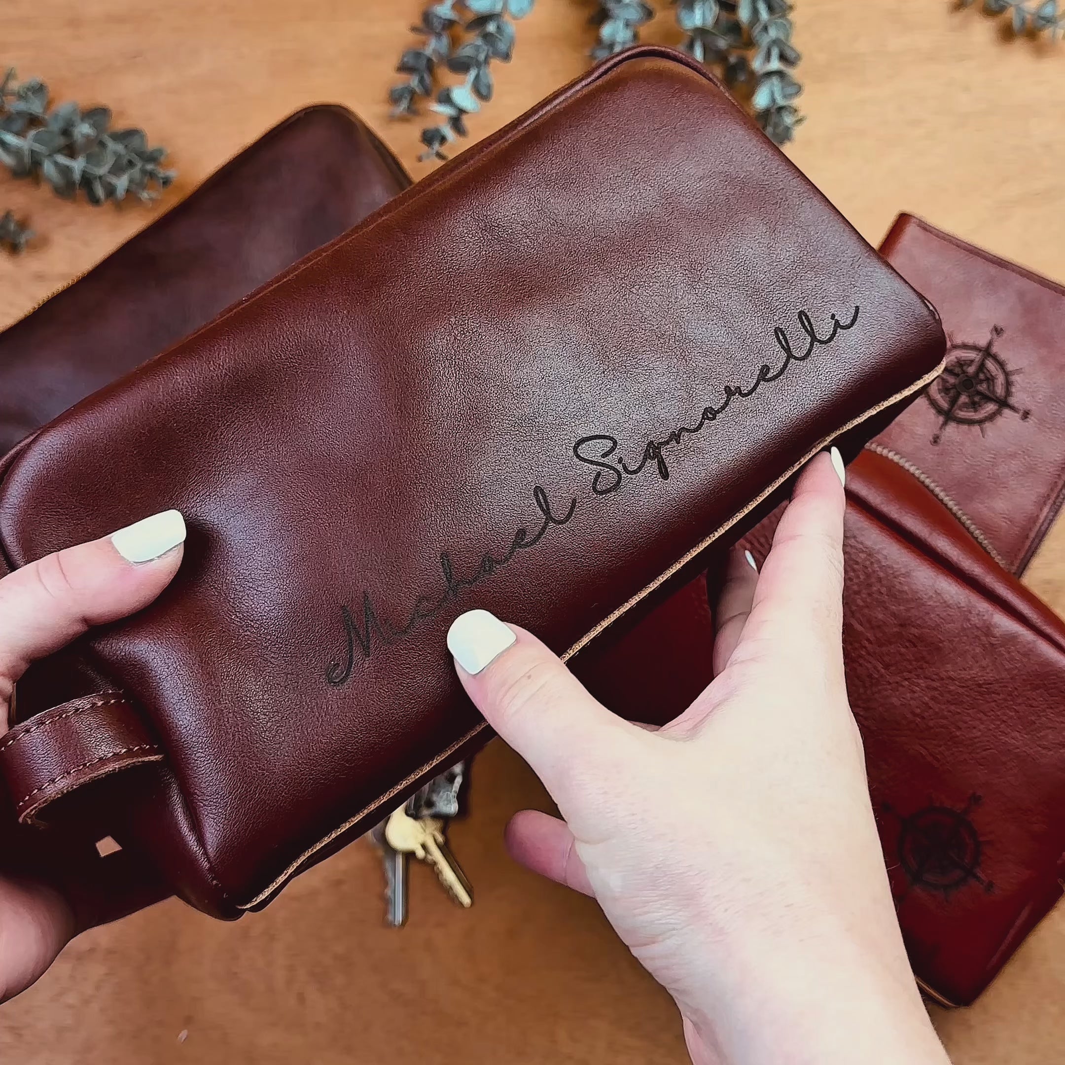 Video showcasing a personalized men’s leather cosmetic bag, or Dopp kit, in rich brown tones, featuring custom compass-style engraving on the side; durable travel toiletry bag and groom’s gift, perfect as a custom engraved Father’s Day, anniversary or groomsmen gift for him.