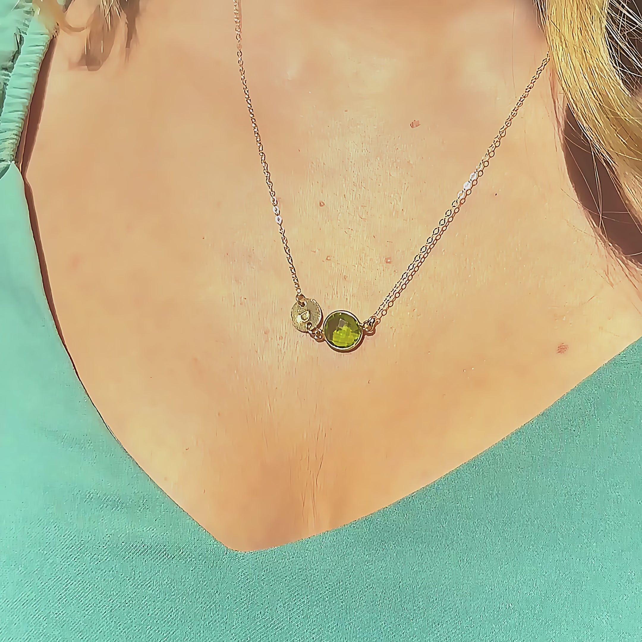 Video of a custom initial birthstone necklace shimmering in the sunlight, featuring a delicate sterling silver chain with one bezel-set round green Peridot birthstone and a tiny engraved initial disc resting at the center of the neckline. Personalized minimalist birthstone jewelry for mom, grandma or best friend, perfect for August birthday, Mother’s Day or everyday wear, meaningful dainty layering necklace gift.
