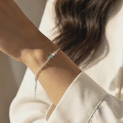 Delicate video of a minimalist custom cabochon birthstone bracelet in sterling silver, gently moving on a woman’s wrist, featuring tiny bezel set round stones that can be personalized with kids’ or family birthstones; dainty stackable chain bracelet perfect for everyday wear, meaningful gift for mom, daughter, sister, bridesmaid or best friend, shown in soft golden light for a modern fine-jewelry look.