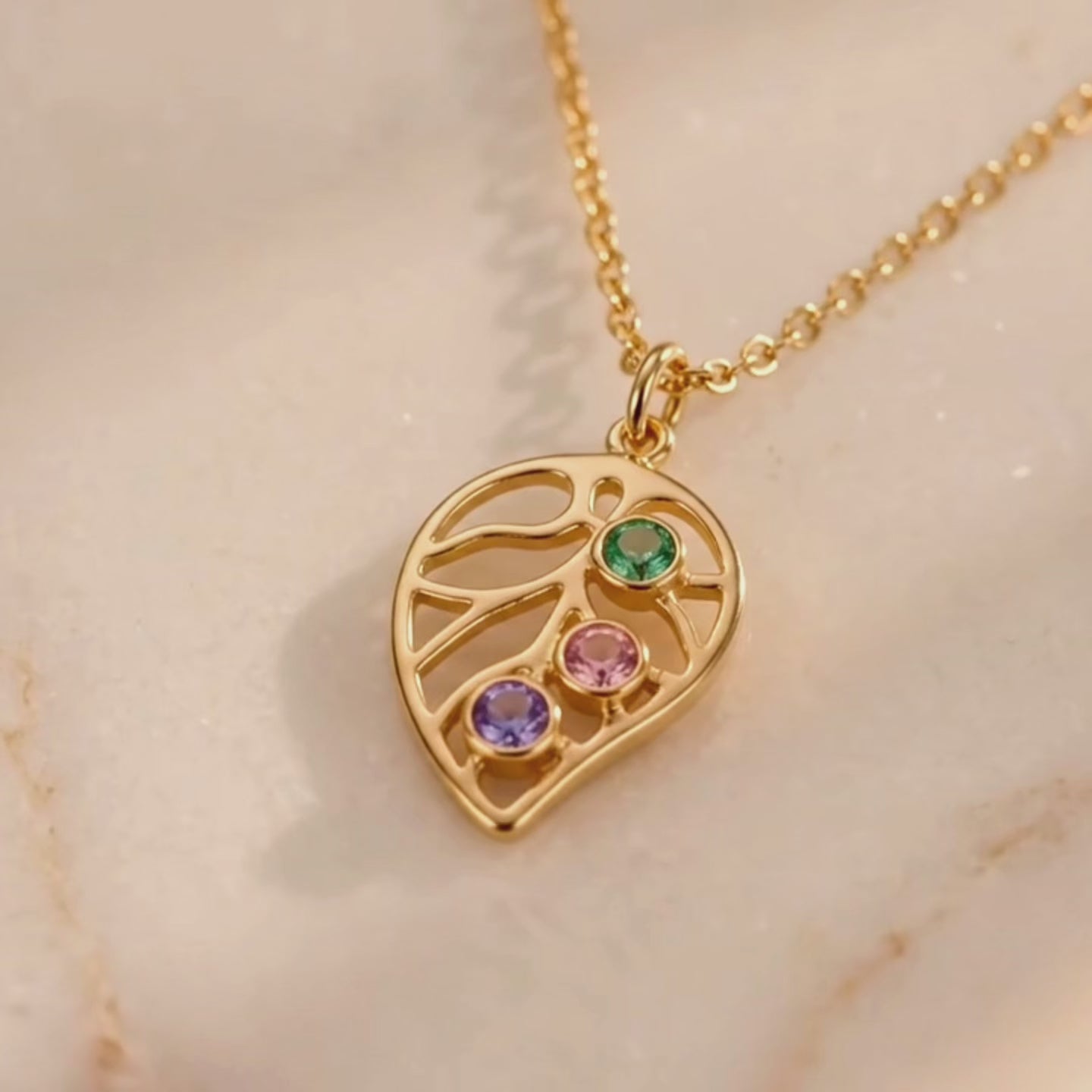 A video showcasing Custom leaf birthstone necklace with up to four colorful stones on a gold chain, personalized family jewelry for mom or grandma.