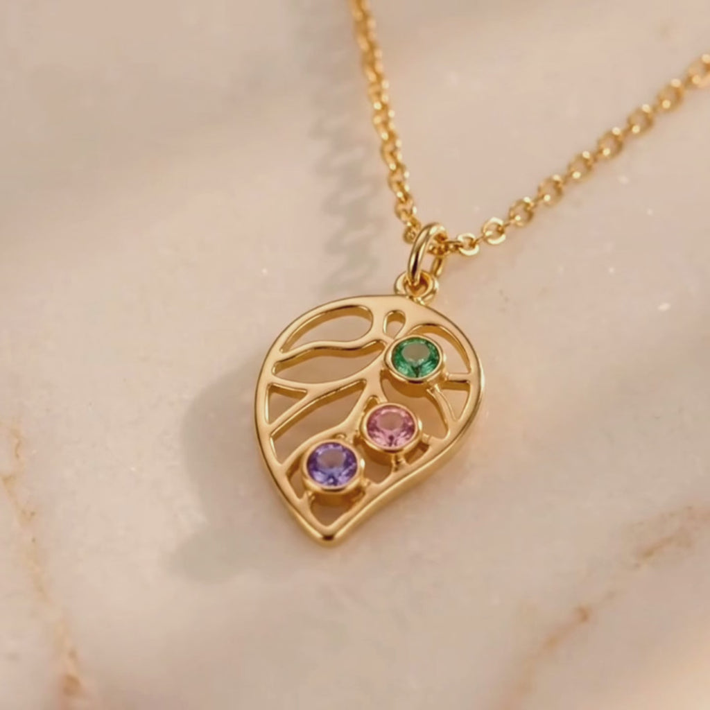 A video showcasing Custom leaf birthstone necklace with up to four colorful stones on a gold chain, personalized family jewelry for mom or grandma.