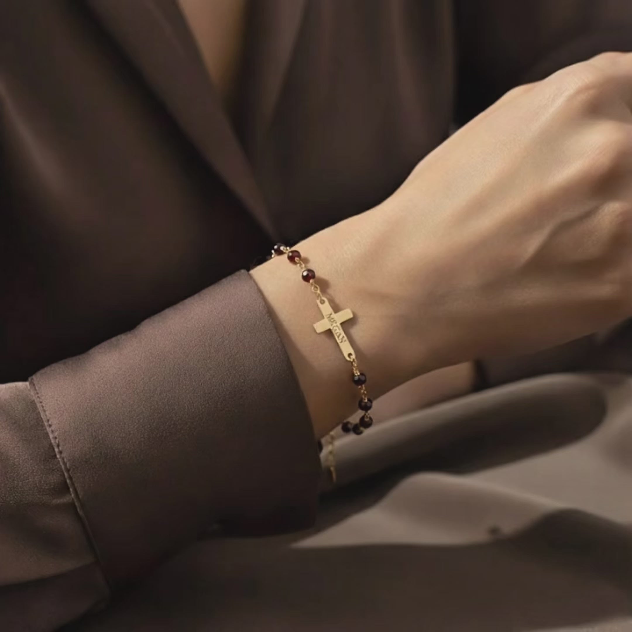 Video showcasing a dainty custom engraved cross bracelet on the wrist, featuring a slim gold bar and cross charm on a wire-wrapped natural gemstone chain; elegant personalized Christian bracelet, meaningful faith jewelry and gift for baptism, confirmation or everyday wear.