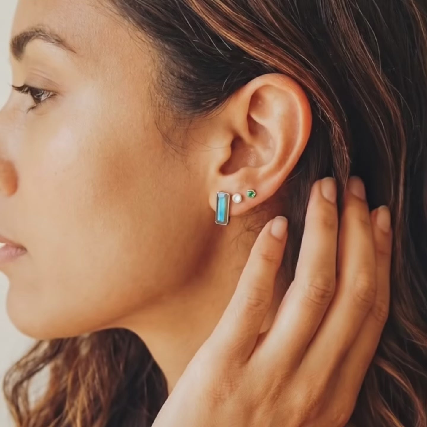 a video showcasing Hand holding tiny baguette birthstone stud earrings