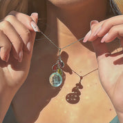 Video showcasing Gold filled cluster birthstone pendant with four bezel set gemstones in soft green, aqua and teal tones, hanging from a dainty chain on a satin beige background, customizable as a personalized family birthstone necklace and meaningful gift for mom, grandma or best friend.