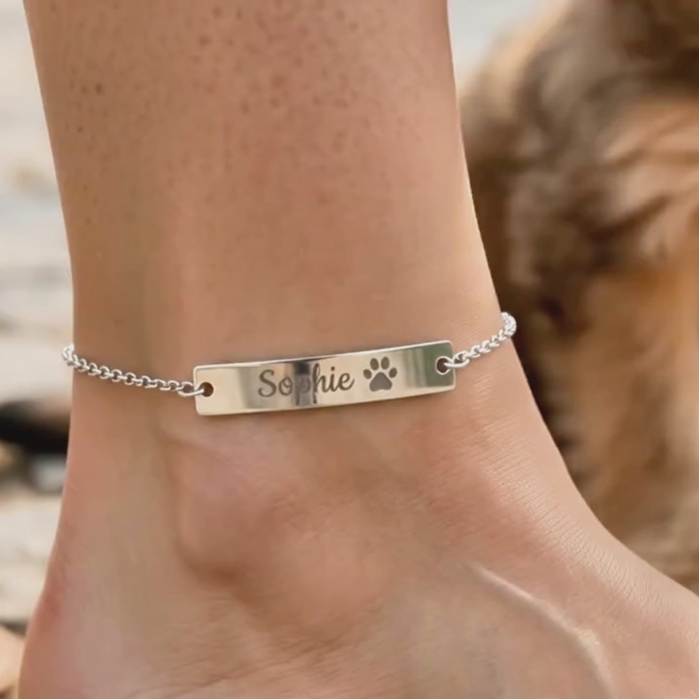 A video showing a personalized pet bar anklet with a pet's name and paw print available in solid sterling silver, 14k gold filled, or 14k rose gold filled.