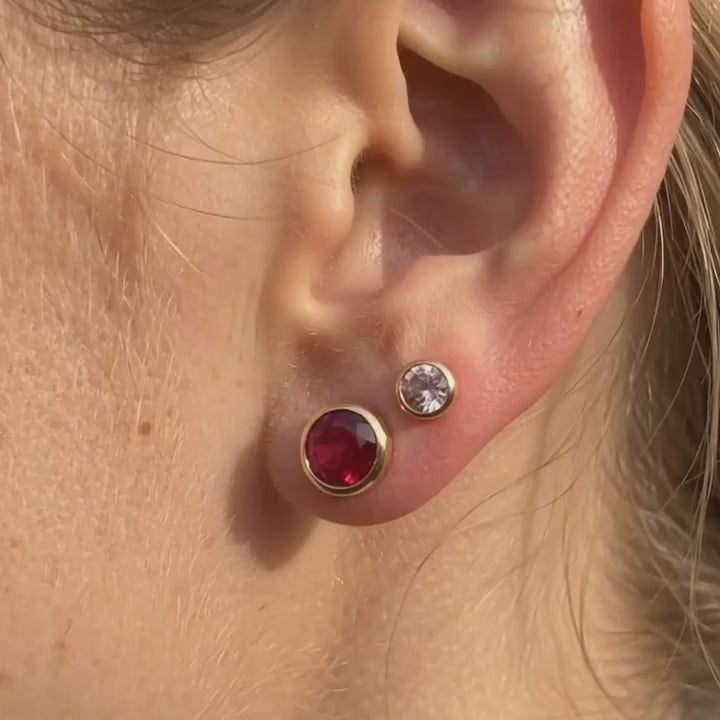 a video showcasing Tiny birthstone stud earrings in gold with colorful gemstones in 3mm and 5mm sizes on soft neutral fabric