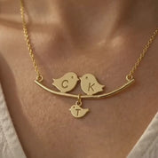 A video showcasing a gold or silver personalized lovebirds family necklace with hand-stamped parent and baby bird initial charms.
