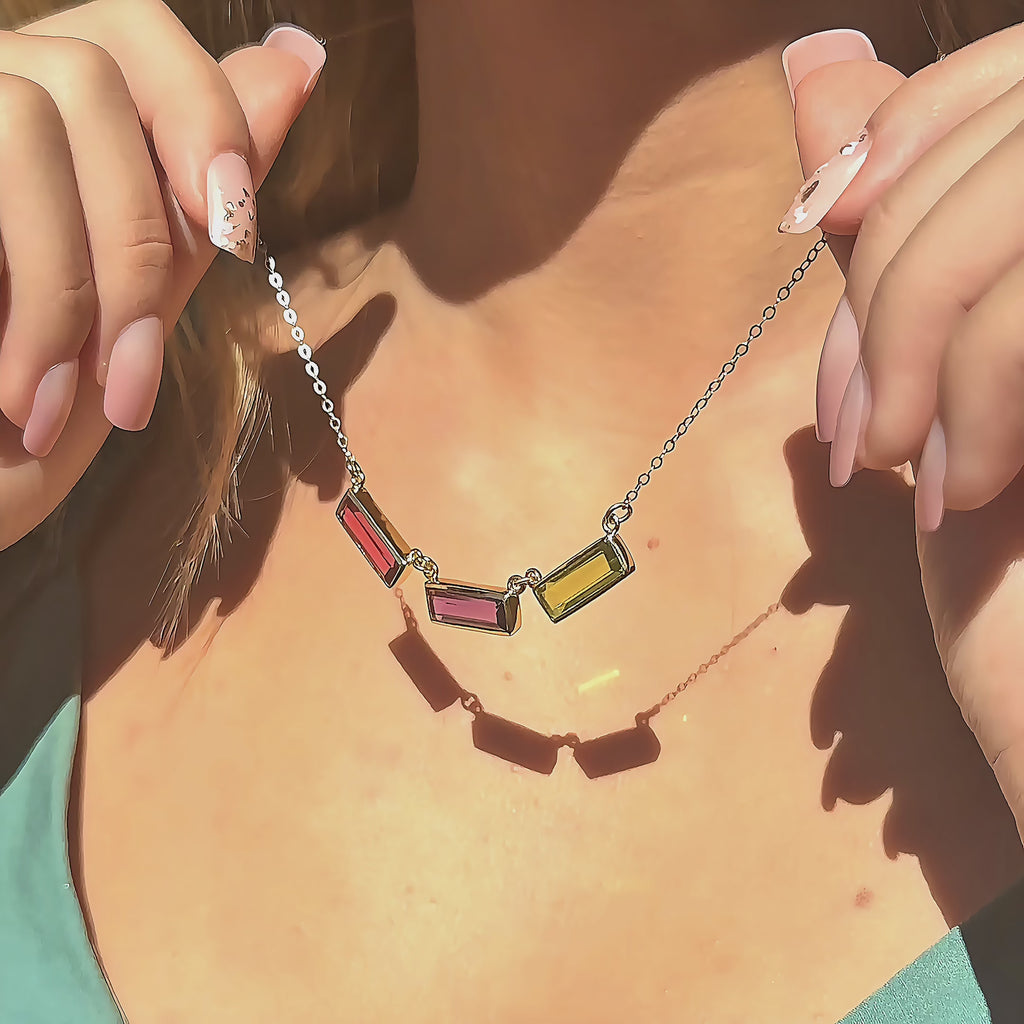 video showcasing custom mom birthstone name necklace with three vertical bar gemstones in gold, featuring blue topaz, ruby and pink quartz bars on a delicate chain, highlighting movement, sparkle and layering style; personalized family jewelry designed to represent children’s birthstones; meaningful Mother’s Day, birthday or Christmas gift idea for moms, grandmas or new moms looking for modern keepsake jewelry