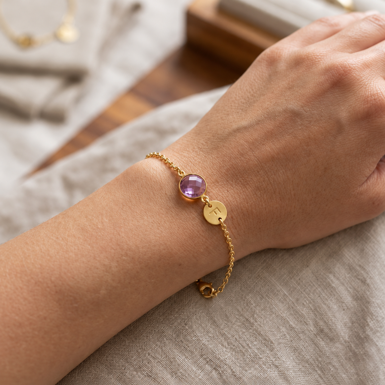 Woman wearing a personalized purple amethyst bracelet with initial charm on her wrist.
