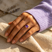 Woman wearing a purple cushion amethyst pave ring with a lavender knit sweater.