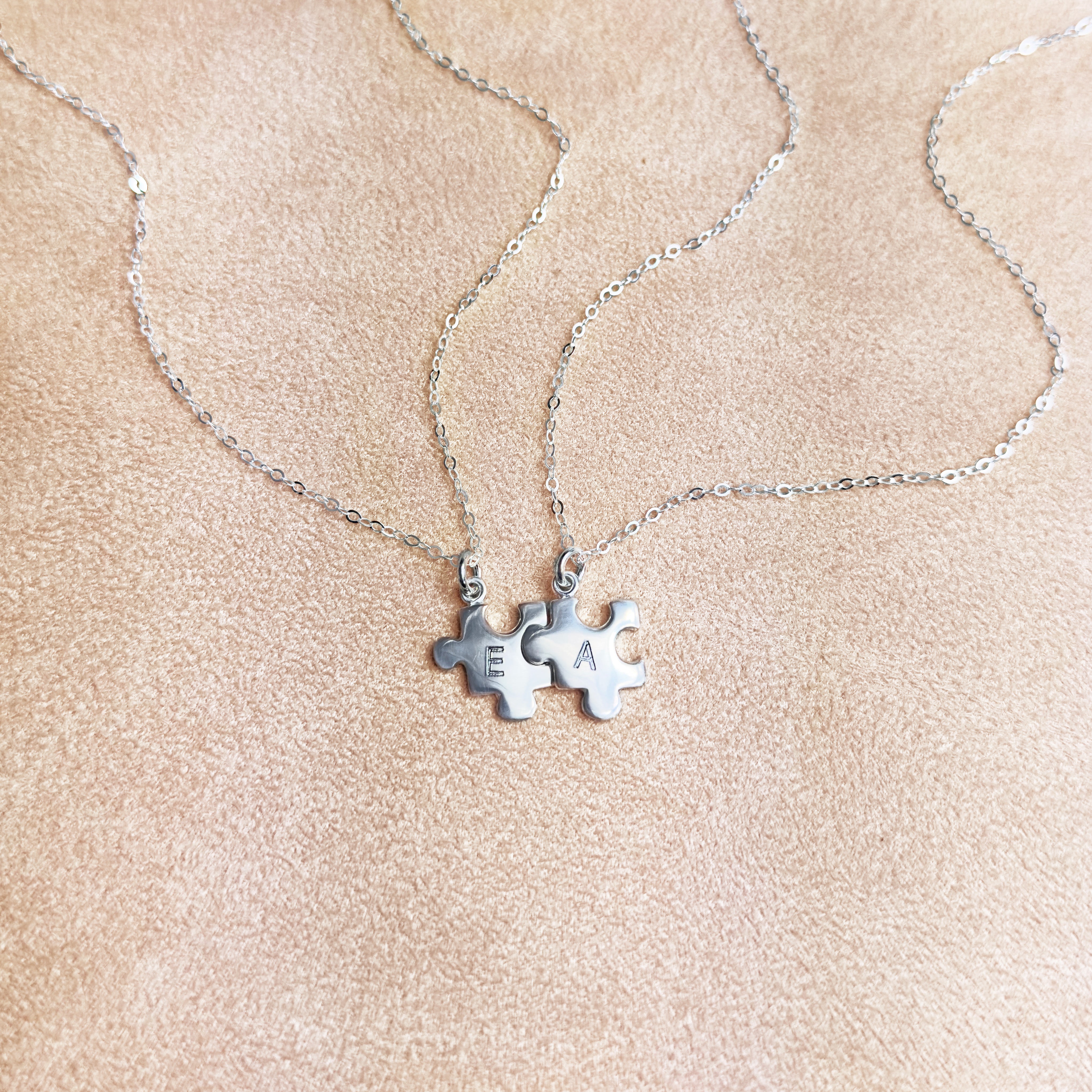 Silver puzzle charm necklace with A initial on beige background. sterling silver or vermeil gold, each charm features a single engraved initial. Whether it’s for your other half, your lifelong best friend, or a bond between mother and child, this necklace makes a meaningful gift for Christmas, Mother’s Day, or Valentine’s Day. layering necklace, puzzle piece, bff jewelry, couples jewelry, bff necklace, couples necklace