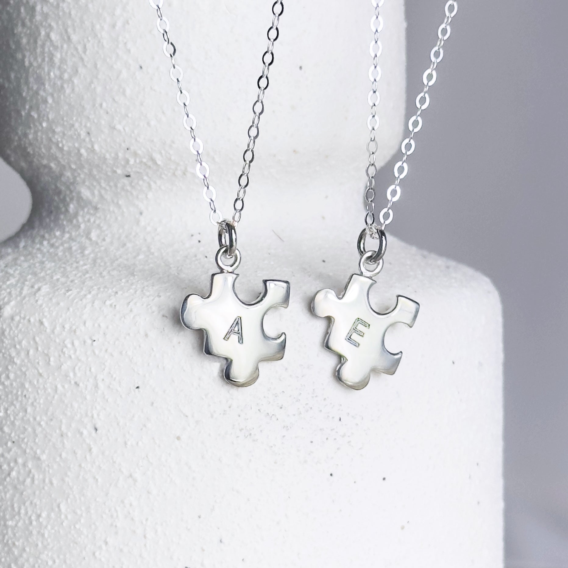 Two Silver puzzle charm necklaces with A and E initial on white background. sterling silver or vermeil gold, each charm features a single engraved initial. Whether it’s for your other half, your lifelong best friend, or a bond between mother and child, this necklace makes a meaningful gift for Christmas, Mother’s Day, or Valentine’s Day. layering necklace, puzzle piece, bff jewelry, couples jewelry, bff necklace, couples necklace