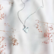 Silver puzzle charm necklace with E initial on beige background. sterling silver or vermeil gold, each charm features a single engraved initial. Whether it’s for your other half, your lifelong best friend, or a bond between mother and child, this necklace makes a meaningful gift for Christmas, Mother’s Day, or Valentine’s Day. layering necklace, puzzle piece, bff jewelry, couples jewelry, bff necklace, couples necklace