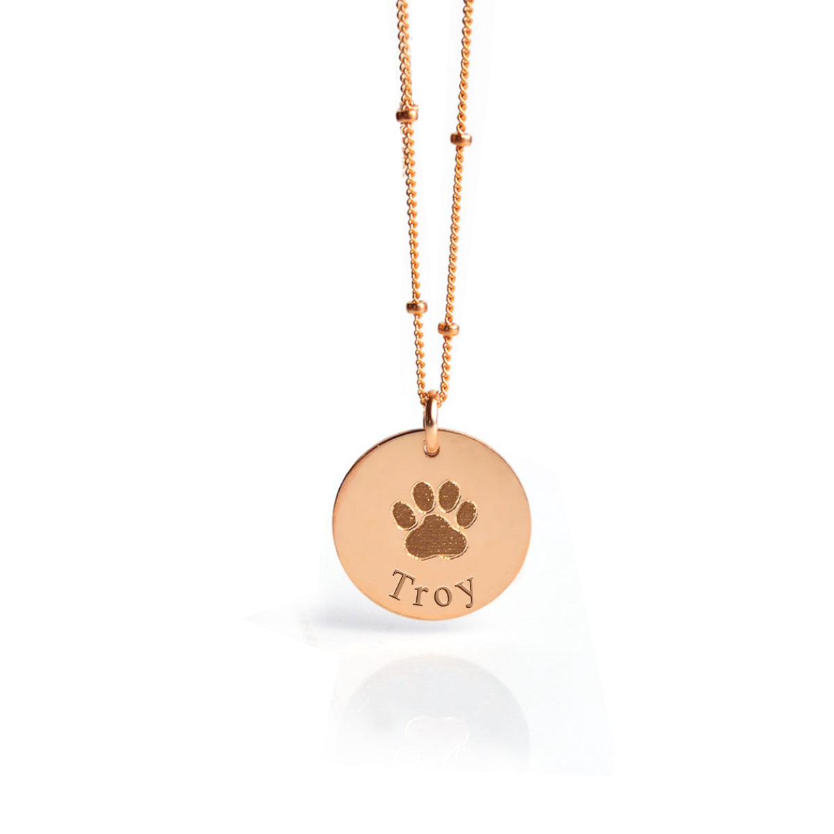Rose gold disc pendant necklace featuring an engraved dog paw print and the name “Troy,” personalized pet memorial jewelry, custom engraved keepsake for pet lovers, unique sympathy gift for dog or cat owners, elegant and minimalist design available in multiple chain styles and lengths, perfect for daily wear or special remembrance occasions.