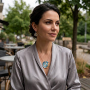 Woman wearing Ocean Breeze Tidal Orbit sculptural pendant necklace with gray satin blouse outdoors