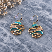 Ocean Breeze Sculptural Wave statement earrings with teal and warm metallic flowing curves on gray stone


