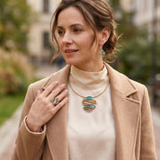 Woman wearing Ocean Breeze Sculptural Wave necklace and matching earrings with neutral outfit
