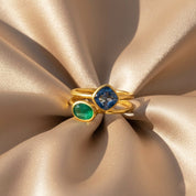 Gold birthstone rings styled on fabric, oval and diamond cut gemstones in bezel settings, personalized stacking rings for women