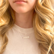 A person with blonde hair wears a silver engraved heartbeat necklace. Personalized bar necklace, minimalist jewelry, layering necklace, ekg jewelry, sonogram jewelry, custom engraved heartbeat necklace, sterling silver necklace, front and back engraved sterling silver necklace for women, gold filled necklace for women, rose gold filled necklace for women