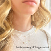 Woman wearing layered skyline bar necklace, personalized engraved city pendant, minimalist everyday travel necklace gift.