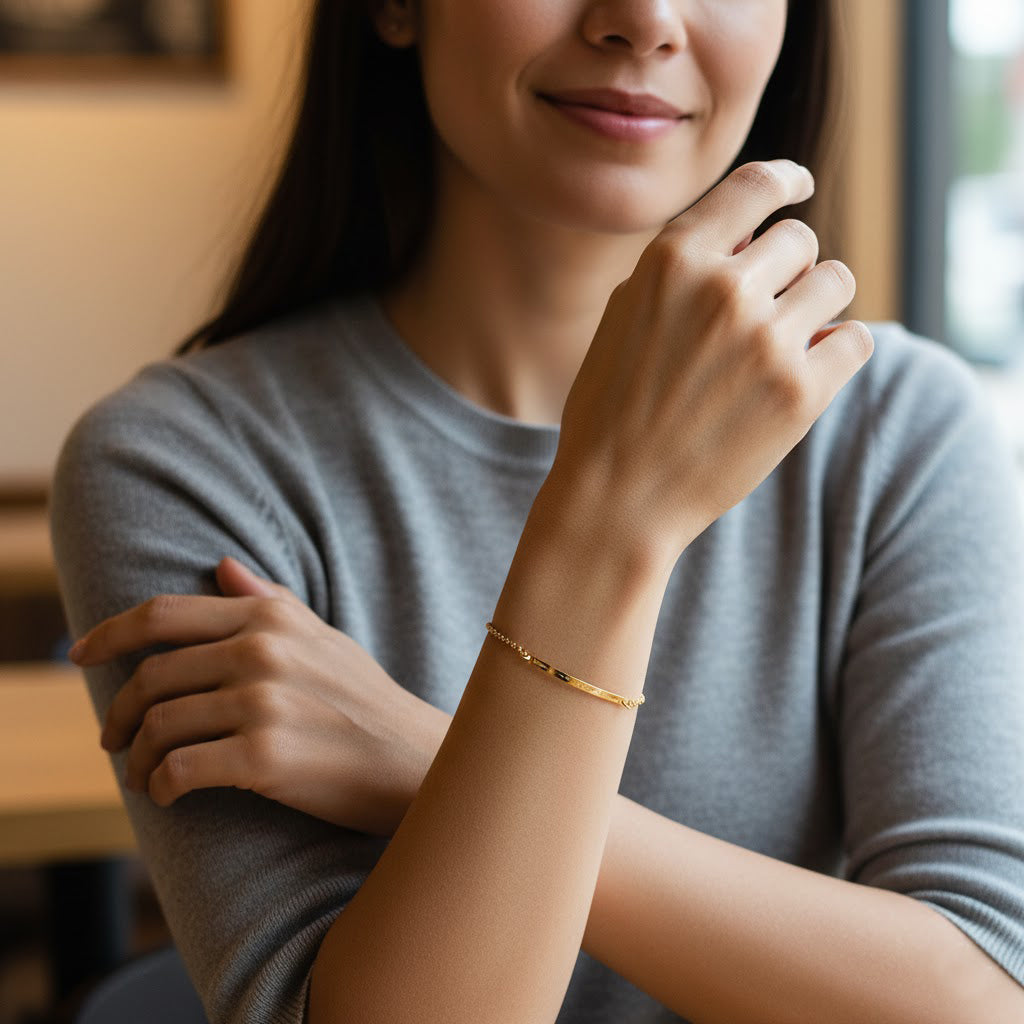 Woman wearing a delicate gold minimalist bracelet with tiny gemstone accents on a fine chain, styled on the wrist in a soft lifestyle setting, showcasing elegant dainty jewelry perfect for everyday wear or personalized birthstone gifts.