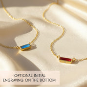 tiny adira birthstone bar necklaces on soft champagne satin, showing two horizontal gemstone bars in vivid blue and rich red set in gold vermeil on delicate chains, each bar engraved with a tiny initial on the bottom to highlight the optional hidden personalization feature, minimalist birthstone bar necklace design available in all months, perfect custom initial jewelry gift for birthdays, bridesmaids, graduations or everyday wear
