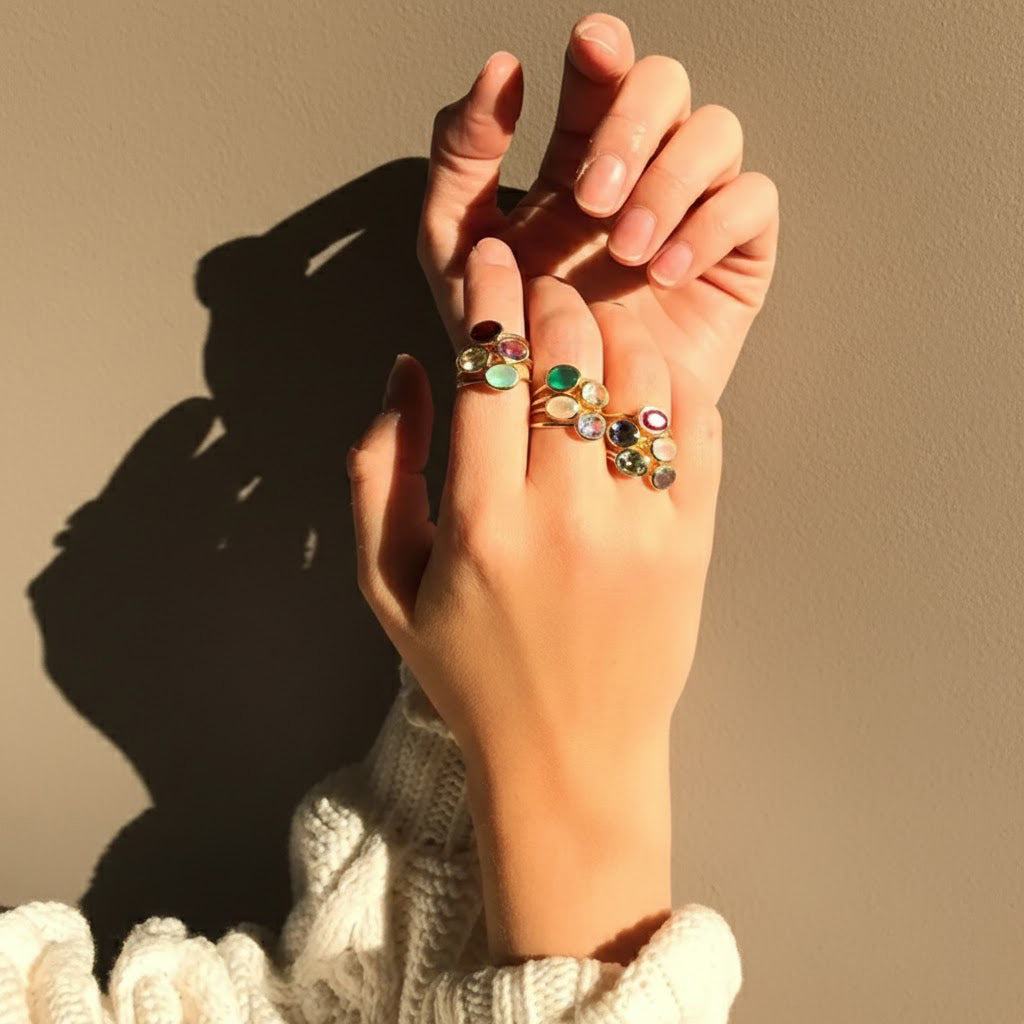 Custom oval gemstone rings glowing in sunlight, featuring aquamarine for March, garnet for January, and citrine for November. Stackable birthstone jewelry for moms, daughters, or best friends.