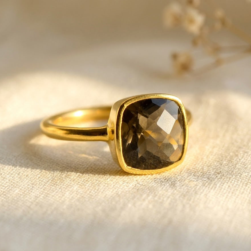 Cushion cut smoky quartz ring in gold bezel setting on neutral background