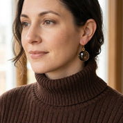 Woman wearing large round Smoky Quartz gemstone earrings with a dark brown turtleneck