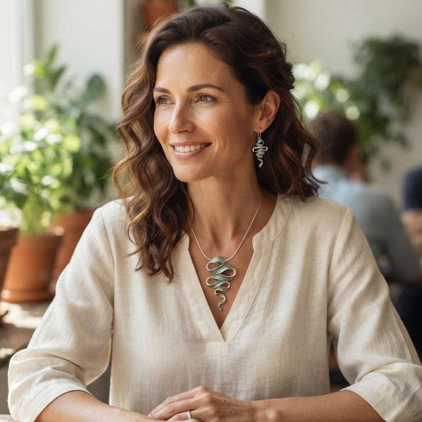 Woman wearing Natural Sage sculptural Ribbon Cascade necklace and earrings with cream blouse