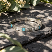 
Silver Mosaic Squares bracelet with teal accent displayed in botanical shadows