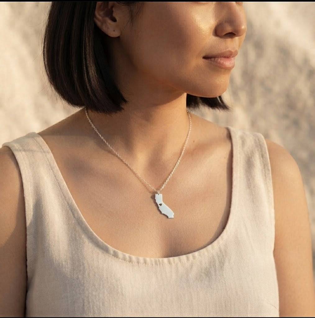 Woman wearing a personalized silver state or county map necklace