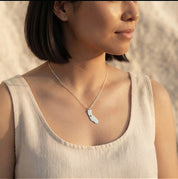 Woman wearing a personalized silver state or county map necklace