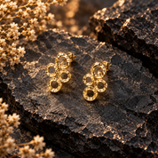 Gold connected circles stud earrings displayed on dark textured stone