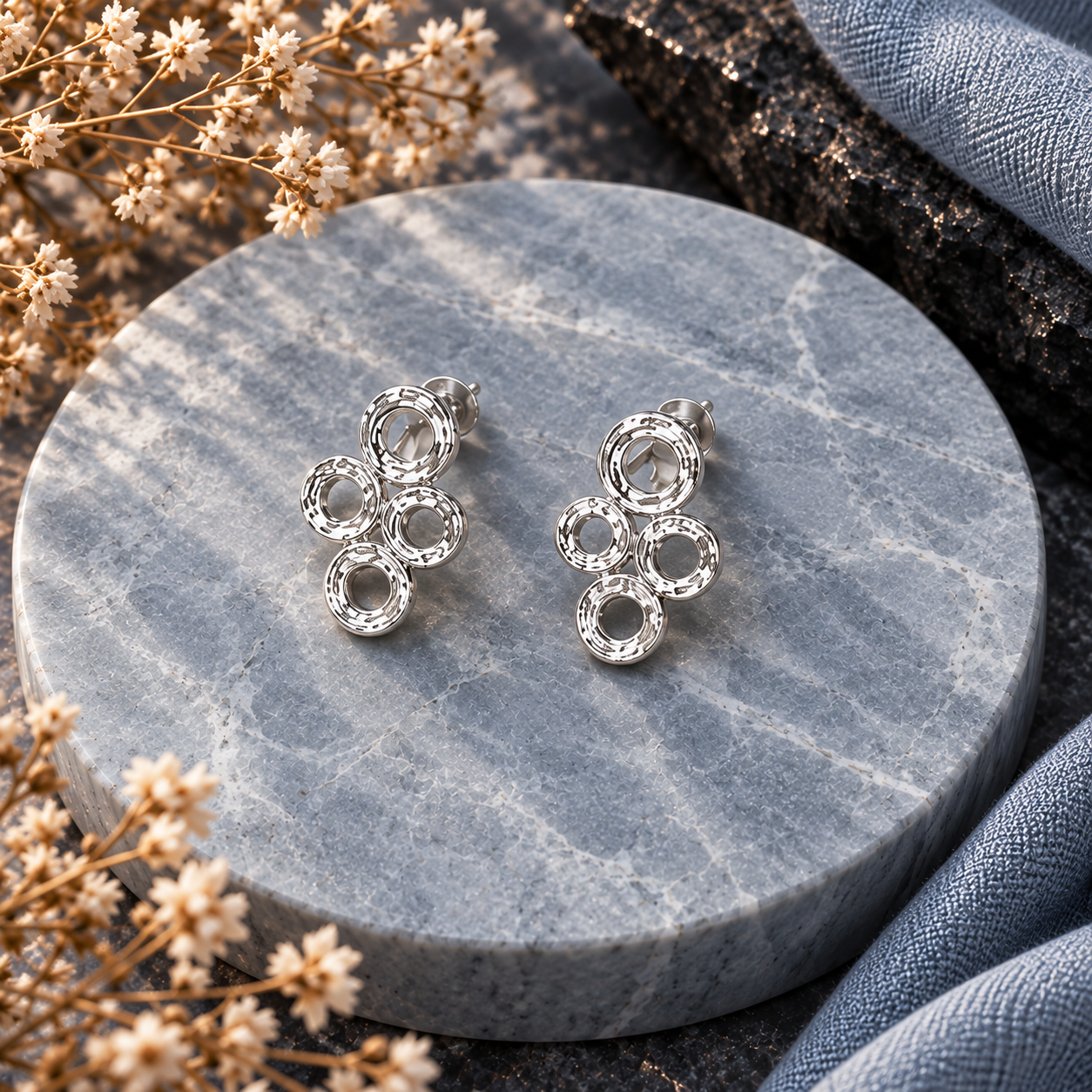 Silver connected circles stud earrings displayed on gray stone background

