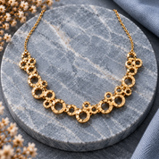 Gold connected circles statement necklace displayed on gray stone background

