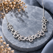 Silver connected circles statement necklace displayed on gray stone background

