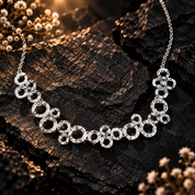 Silver boho connected circles geometric necklace displayed on dark stone

