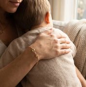 Mother holding child’s hands while wearing a custom sunburst birthstone bracelet, symbolizing family connection and love. Personalized mom bracelet featuring children’s birthstones as a meaningful keepsake.