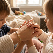 Mother holding her child while wearing a custom sunburst birthstone bracelet featuring ruby for July and peridot for August. Personalized mother and child jewelry symbolizing love, warmth, and family connection.