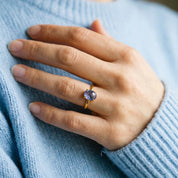 Woman wearing a natural blue violet Tanzanite cabochon ring with a light blue sweater.
