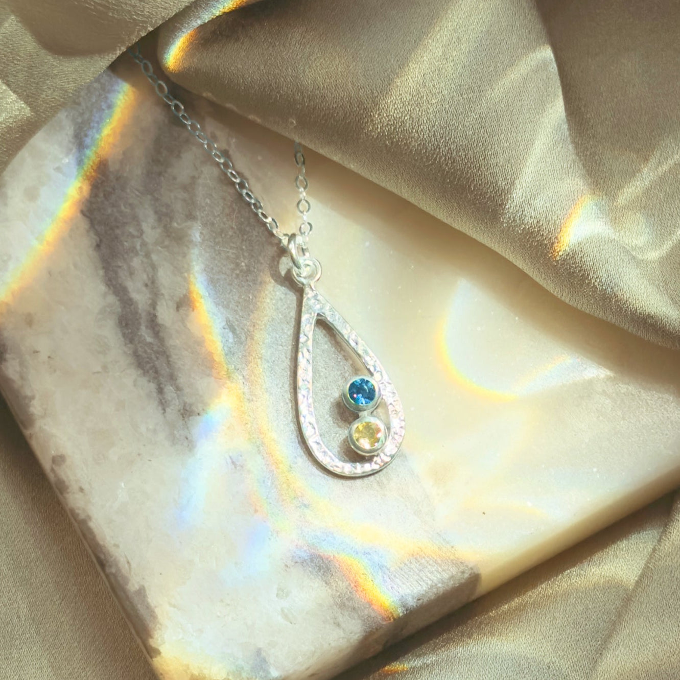 Necklace with a pendant on a reflective surface with fabric background