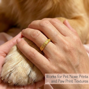 Custom pet print ring shown beside a dog paw and hand to demonstrate it can be engraved from a real nose print texture and can also work for paw print textures, a personalized pet memorial ring and keepsake jewelry for dog lovers, meaningful loss gift for rainbow bridge remembrance, high shine polished band with fine detail engraving, optional inside message for name date or heartfelt words, comfortable everyday fit for stacking or solo wear.