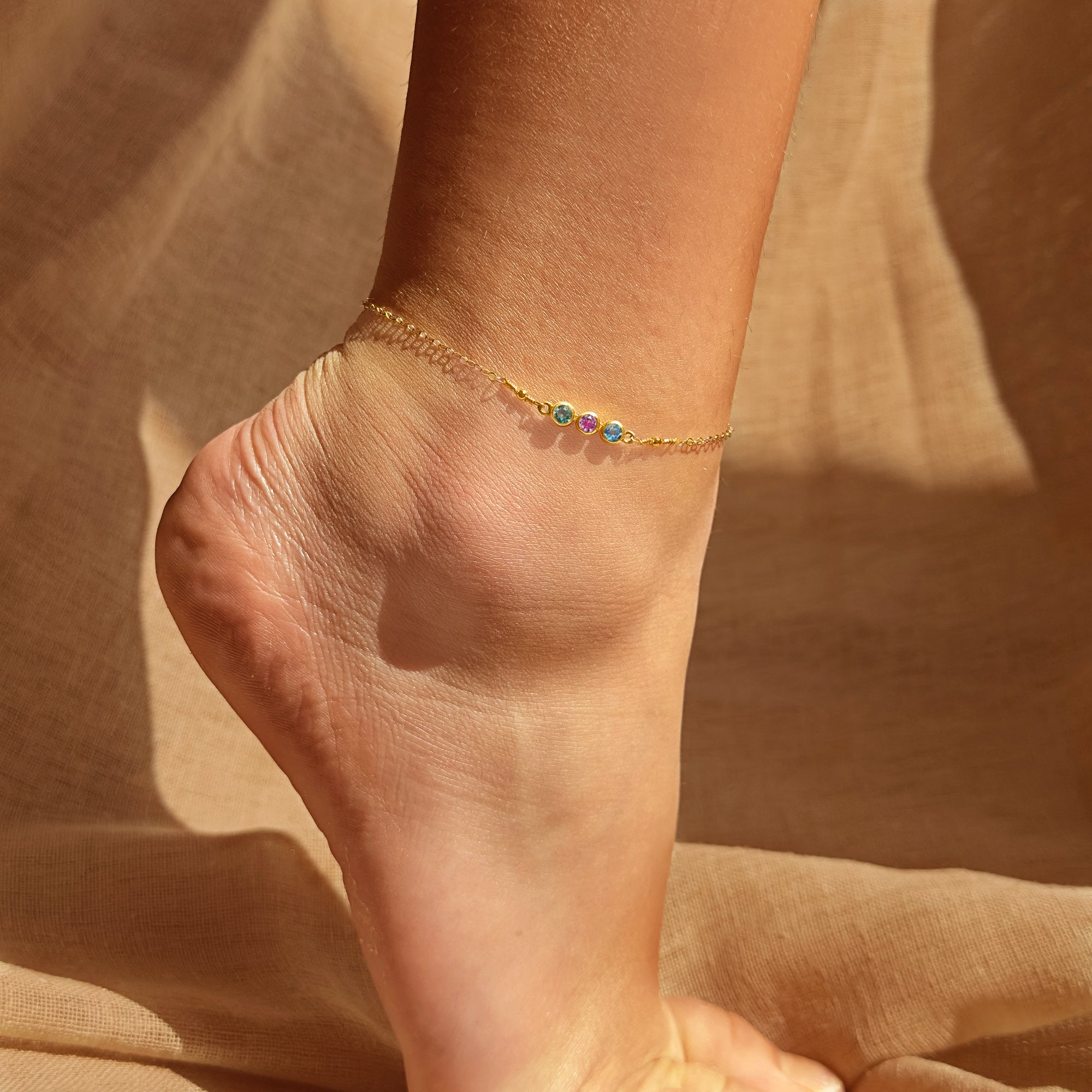 Personalized birthstone bar anklet in gold, shown worn on the ankle, featuring sparkling gemstones that symbolize family members or special milestones. This dainty anklet is adjustable for comfort and available in sterling silver, gold, or rose gold. A minimalist and meaningful jewelry gift for moms, daughters, or best friends, this anklet makes a thoughtful birthday present, Mother’s Day keepsake, or summer accessory.