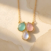 Custom three birthstone necklace with aqua, pink, and moonstone teardrop gemstones on a delicate gold chain, personalized family jewelry for mom.
